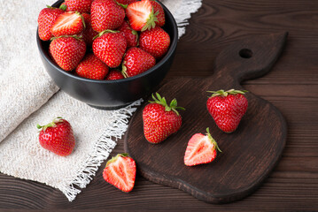 Wall Mural - Bowl of fresh red strawberries on black wooden table. Studio shot of strawberry