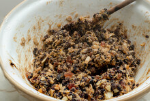 The Ingredients Of Christmas Fruit Cake Are Stirred In A Large Clay Bowl