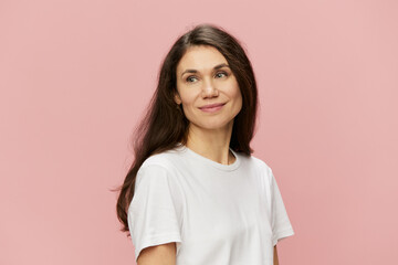 Wall Mural - horizontal portrait of a cute attractive woman on a pink background in a clean white tank top smiling pleasantly at the camera