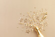 Champagne bottle with gold confetti stars, holiday decoration and party streamers on light festive background. Christmas, birthday or New Year concept.