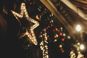 Wall Mural - Merry Christmas! Stylish christmas star illumination and festive lights on fir branches in evening outdoor. Modern christmas decor in city street. Atmospheric winter holidays in Europe.