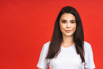 Wall Mural - Portrait of happy smiling brunette girl in casual isolated over red background.