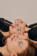 Wall Mural - Portrait of young beautiful women in black jackets lying on floor closely, posing over grey background