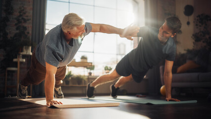 Wall Mural - Middle Aged Man Exercising at Home with Personal Trainer. Senior Male Strengthening Body Muscles with Push-Ups Workout. Son Training with Sporty Father, Motivating Each Other by Giving a High Five.