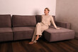 © Шамиль Алиев - A young girl in a homemade suit barefoot sitting on a brown sofa in the room
