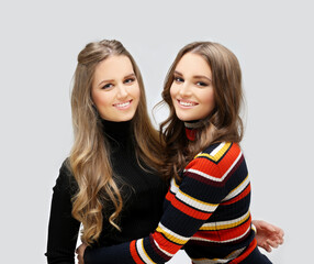 Wall Mural - Beauty portrait of a young girls. two young beautiful girls  standing near a gray background