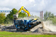Mobile concrete and reinforced concrete construction debris crushing machine in operation