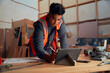 © StratfordProductions - Young man in reflective clothing writing with digitized pen on digital tablet in woodworking factory