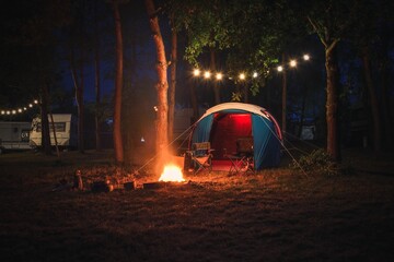 Atmospheric night adventure. Tent with a midnight fire in the forest.