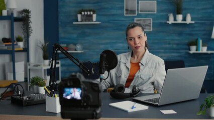 Canvas Print - Attractive social media influencer sitting at home studio desk while getting ready for live broadcast. Creative digital content creator in living room with professional audio equipment filming video.