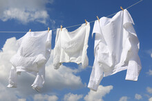 Clean Clothes Hanging On Washing Line Against Sky. Drying Laundry