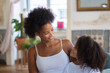 © KAMPUS - Portrait of loving curly mother and daughter. African American woman and little girl looking at each other and smiling. Family, parenthood, home concept