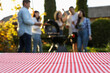 © New Africa - Empty table and blurred view of friends having barbecue party outdoors. Space for text