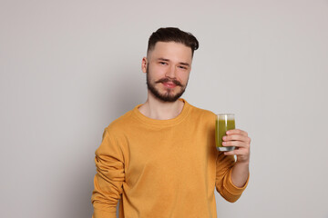 Wall Mural - Handsome young man with glass of juice on light grey background