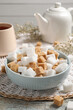 Different refined sugar cubes in bowl on rustic table