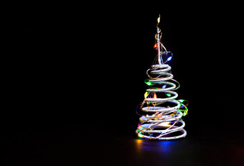 Wall Mural - spiral in the form of a christmas tree with a garland on a black background