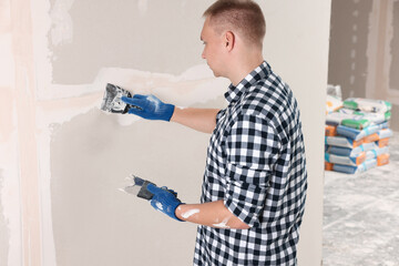 Canvas Print - Man plastering wall with putty knife indoors. Home renovation