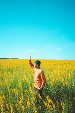 Asian Man Raised Hand, Protecting From The Sunlight, Standing In Jute Tree. Yellow Flower Field At Spring.