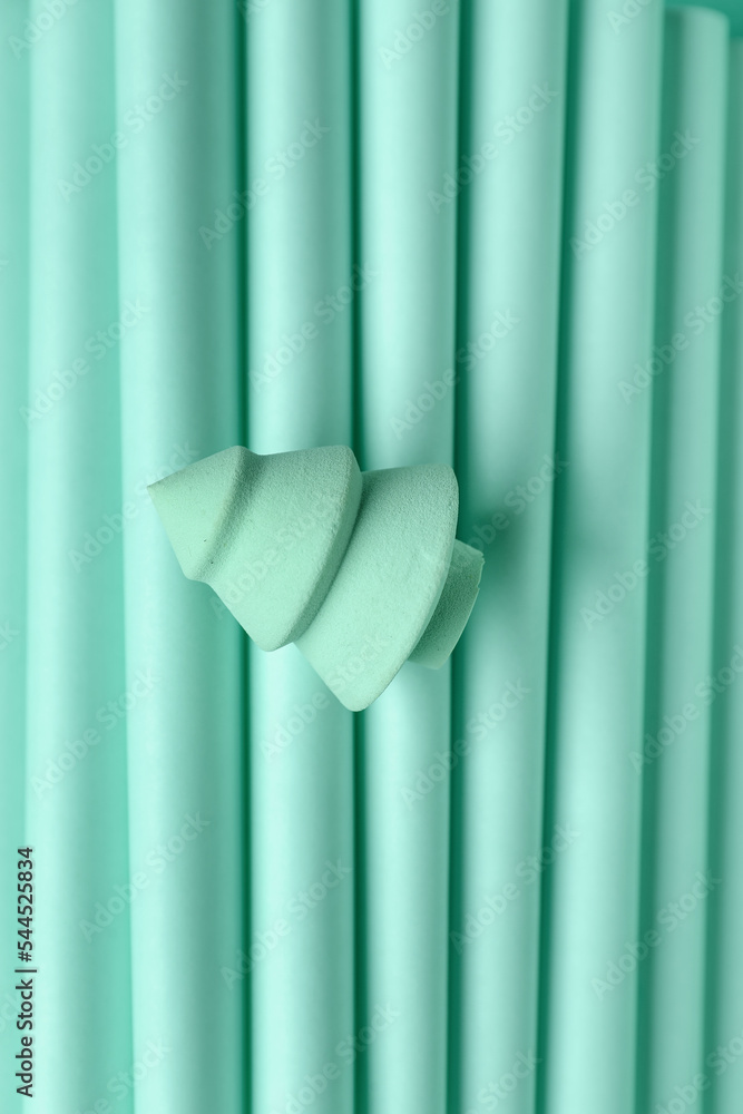 Makeup sponge in shape of Christmas tree on mint background