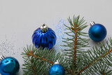 Fototapeta Kawa jest smaczna - Fir branch with blue Christmas balls on grey background, closeup