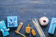 Tasty doughnut with dreidels, candles, rattle and gifts for Hannukah celebration on blue wooden background