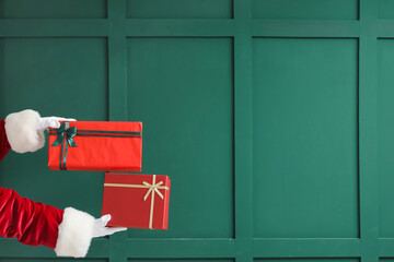 Santa Claus with Christmas presents near green wall