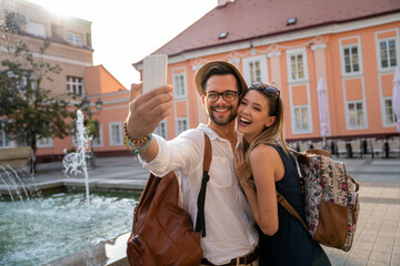 Wall Mural - happy traveling couple taking selfie, having fun on vacation. people technology happiness concept.
