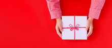 Banner Gift Box In Children's Hands On A Red Background, Presenting A Gift