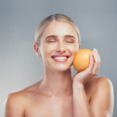 Wall Mural - Woman, smile and orange fruit for skincare, beauty and health against grey studio background for cosmetics. Model, skin and face health for self care, vitamin c and cosmetic for organic dermatology