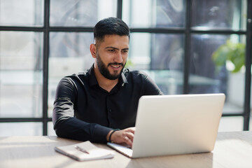 Bearded young businessman working on modern office. Consultant man thinking looking in monitor computer