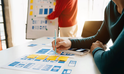  UX developer and ui designer brainstorming about mobile app interface wireframe design with customer breif and color code at modern office.