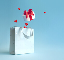 Wall Mural - Shopping bag with gift box and hearts on blue background. St. Valentines Day shopping and discounts concept.