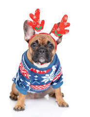 Wall Mural - French Bulldog puppy wearing funny horns and warm sweater sits and looks at camera. Isolated on white background