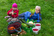 Two happy little girls are holding fresh salad and zucchini in autumn garden after harvesting vegetables  Rural scene outdoors