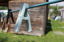 Old Clothespins On A Rope In Summer Weather Against The Background Of A Wooden Structure And A Blue Sky.