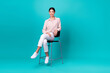 © deagreez - Full size photo of young korean lady sit bar chair relaxing toothy smile wear stylish smart casual outfit isolated on cyan color background
