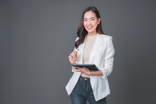 Fototapete - Young asian woman confident manager worker use modern technology digital tablet work remote distance isolated grey color background. Beautiful woman using smartphone. Lifestyle concept.