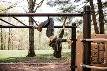 Boy At Playground Hanging On Monkey Bars