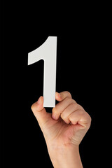 Aufkleber - Number one in a hand isolated on a black background. Number one white in a child's hand on a black background.