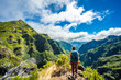 Woman enjoying mountain scenery from very scenic view point along hike trail to Pico Ruivo at noon. Pico do Arieiro, Madeira Island, Portugal, Europe.