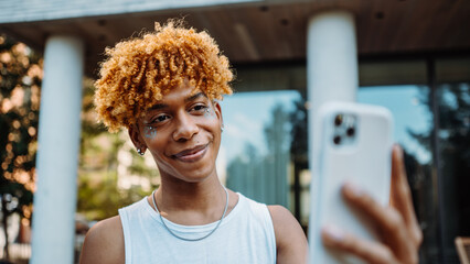 Wall Mural - Young multiracial man having online video call on smartphone app with friend