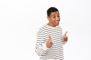 Wall Mural - Smiling african american man pointing fingers at you, congratulating, inviting people, standing over white background