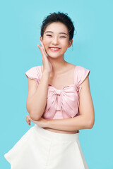 Wall Mural - A beautiful asian young girl without acne or blemishes, white smile, touching face and looking happy, standing over cyan background