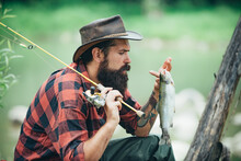 Portrait Of Young Bearded Man Fishing At A Lake Or River. Flyfishing. Fishing Hobby And Spring Weekend.