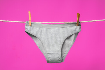 Wall Mural - Female panties hanging on rope against pink studio background