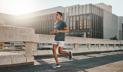 Fitness, health and city man running on street with motivation, healthy mindset and summer morning energy for training. Urban workout, cardio exercise and runner on bridge, focus on sports lifestyle.