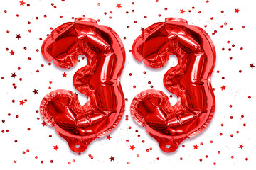 Wall Mural - The number of the balloon made of red foil, the number thirty-three on a white background with sequins. Birthday greeting card with inscription 33. Numerical digit, Celebration event.