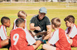 © L Ismail/peopleimages.com - Teamwork, coaching and football with children on field for training, fitness and sports goals. Planning, pitch and strategy with mentor and soccer player kids learning for exercise, games and manager
