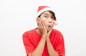 expressive happy young asian man in christmas santa theme clothes wit shocked, surprised and amazed face expression. wow expression man in red santa hat. christmas model concept for sale and discount.