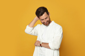 Wall Mural - Portrait of smiling bearded man with wristwatch on orange background